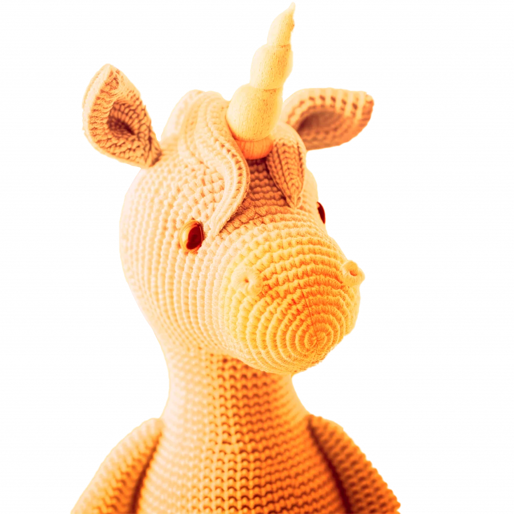 Ein Bild von einem Goldgelbenden Stofftier Einhorn, bestehend aus großen Strick-Maschen und einem Horn aus Holz.