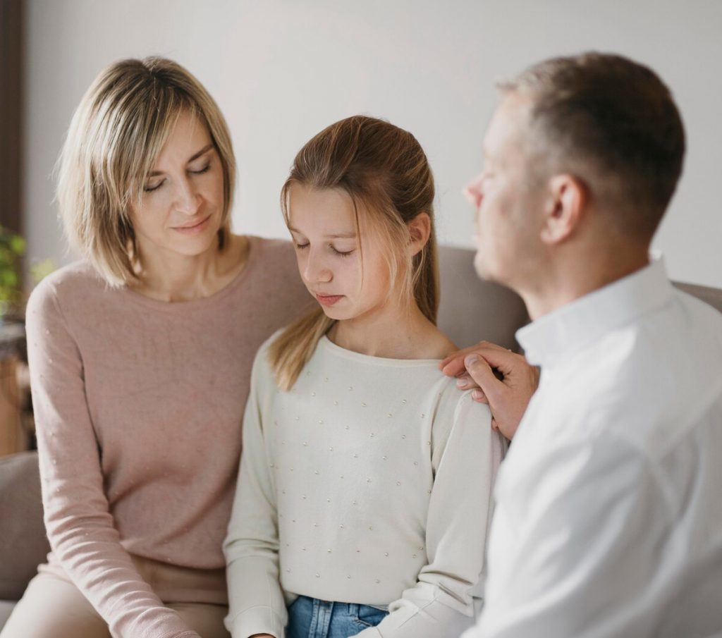 Ein Bild von einem Elternpaar, das gemeinsam mit deren Tochter betet.